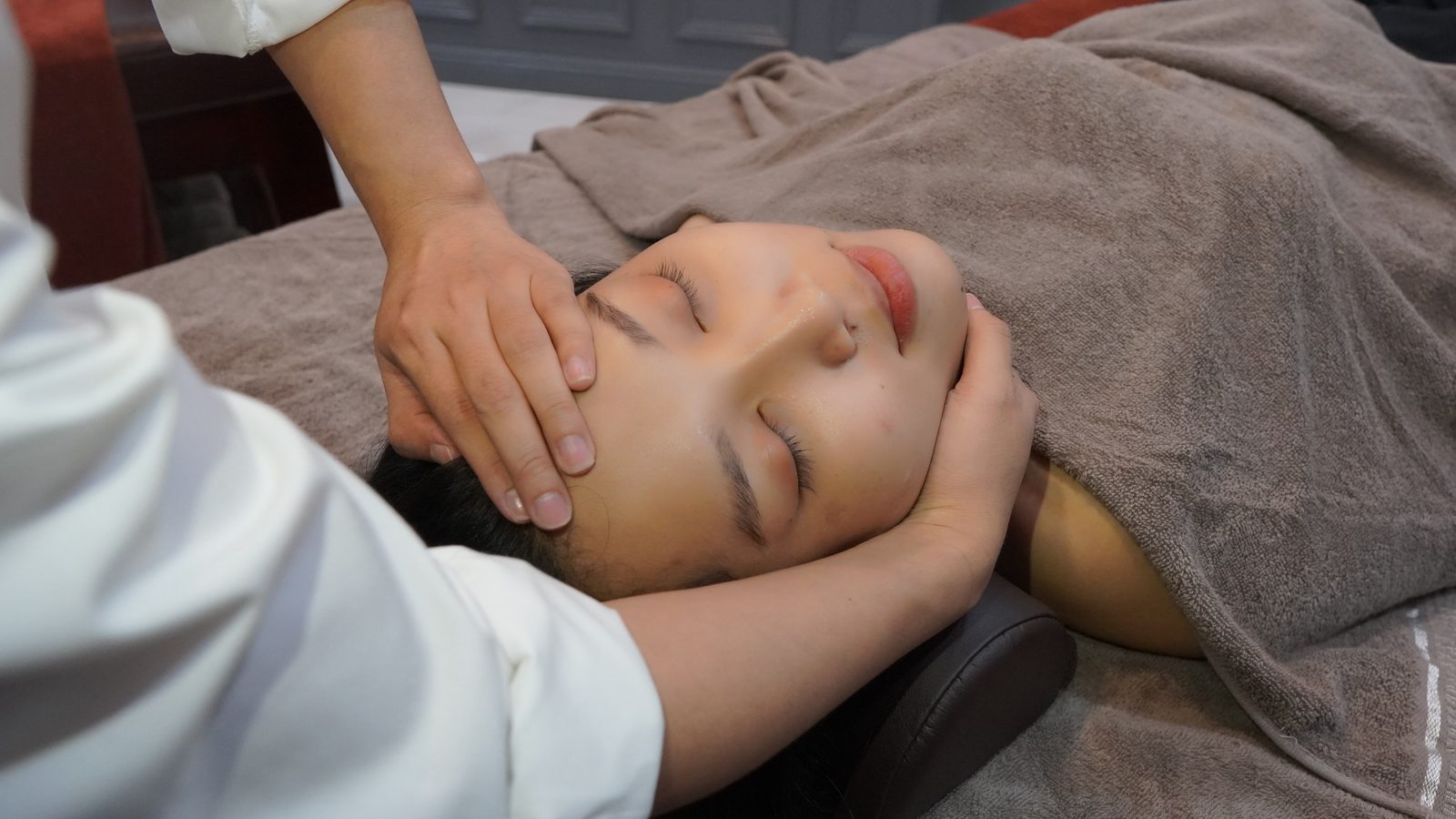 A therapist's hands resting gently on a guest's face during a facial
